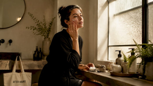 Woman applying moisturizer to skin at vanity