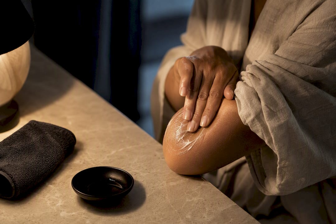 Hands moisturising a dry elbow at night