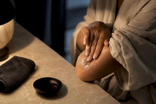 Hands moisturising a dry elbow at night