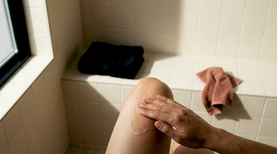 Hand applying moisturizer to shaved knee